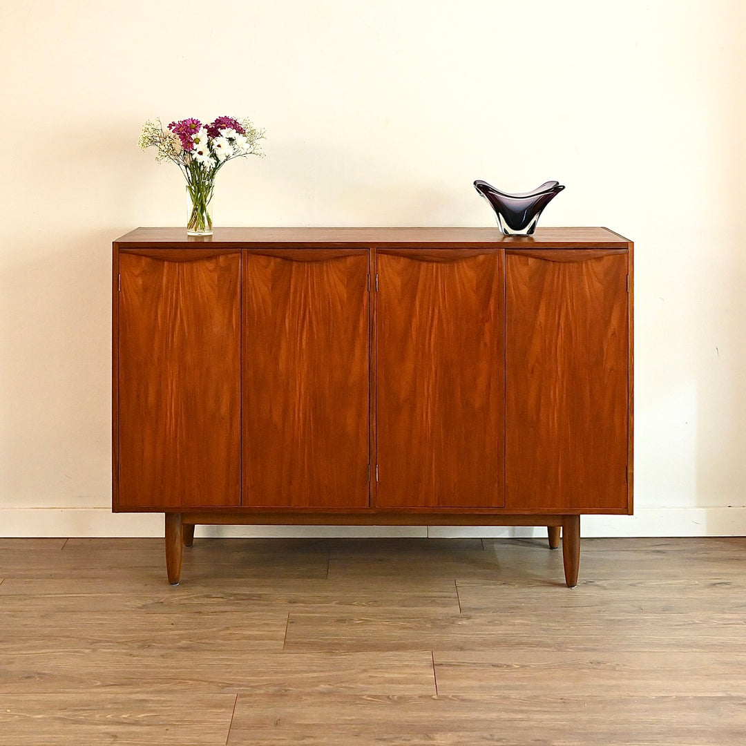 Wooden sideboard with decorative items on a wooden floor and beige wall